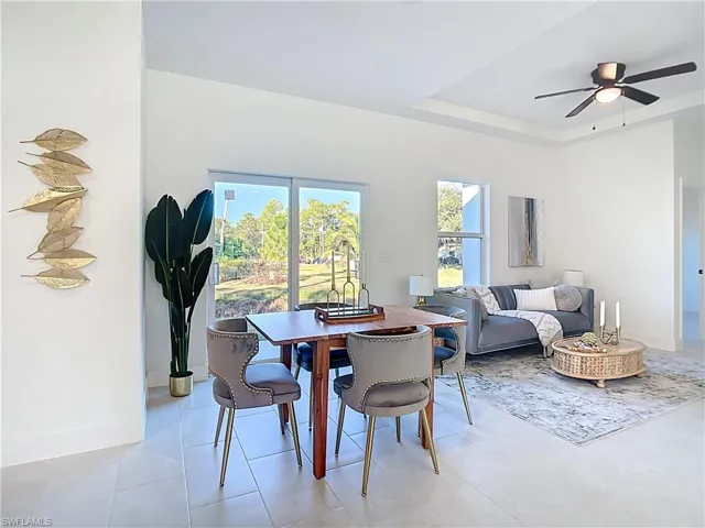 Open-concept living area featuring a tray ceiling, ceiling fan, and large sliding glass doors