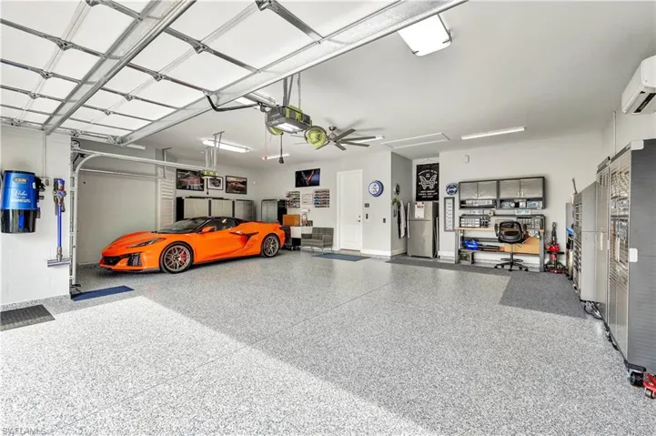 Garage with a garage door opener, freestanding refrigerator, and a wall unit AC