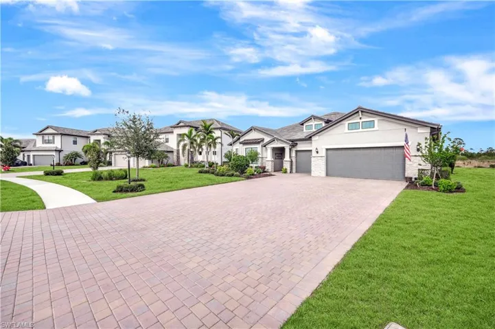 View of front of house featuring decorative driveway, a garage, a residential view, stone siding, and a front lawn