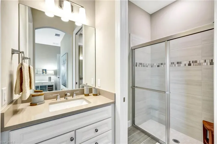 Bathroom featuring visible vents, a shower stall, and vanity