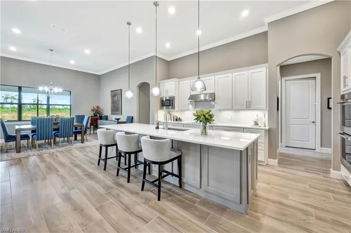 Kitchen with light countertops, stainless steel microwave, white cabinetry, and pendant lighting