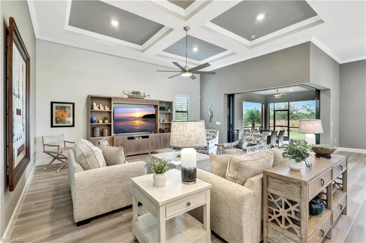 Living room with wood tiled floor, coffered ceiling, a towering ceiling, and baseboards