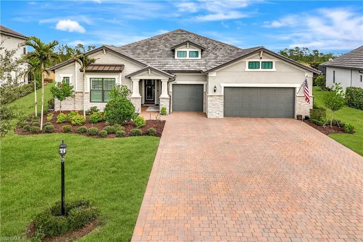 View of front facade with stone siding, a front lawn, decorative driveway, and stucco siding