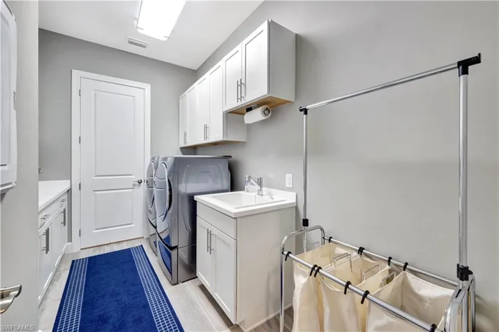 Washroom with visible vents, separate washer and dryer, a sink, and cabinet space