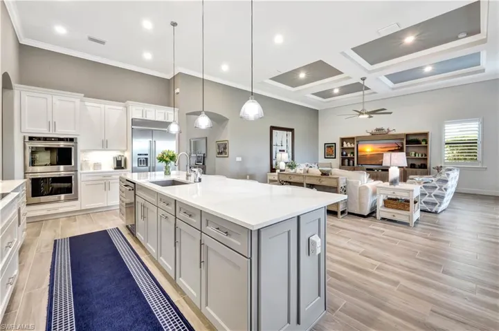 Kitchen with light countertops, appliances with stainless steel finishes, a sink, and pendant lighting