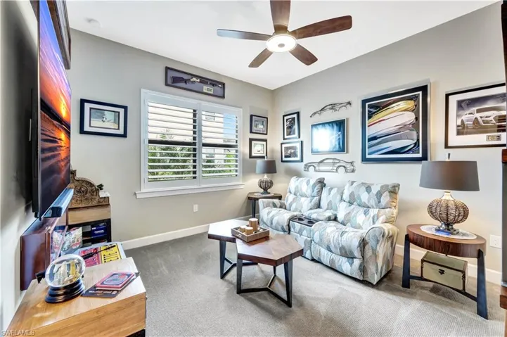 Living area featuring dark carpet, baseboards, and ceiling fan