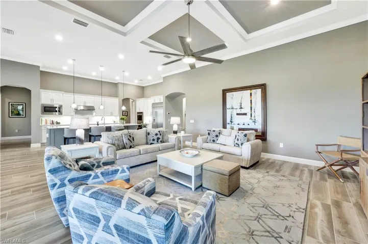 Living room with arched walkways, coffered ceiling, visible vents, a ceiling fan, and light wood-type flooring