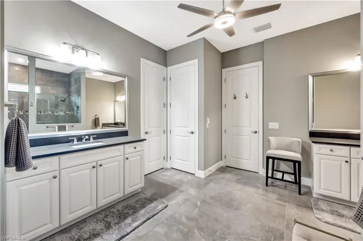 Full bathroom with baseboards, visible vents, a ceiling fan, walk in shower, and vanity