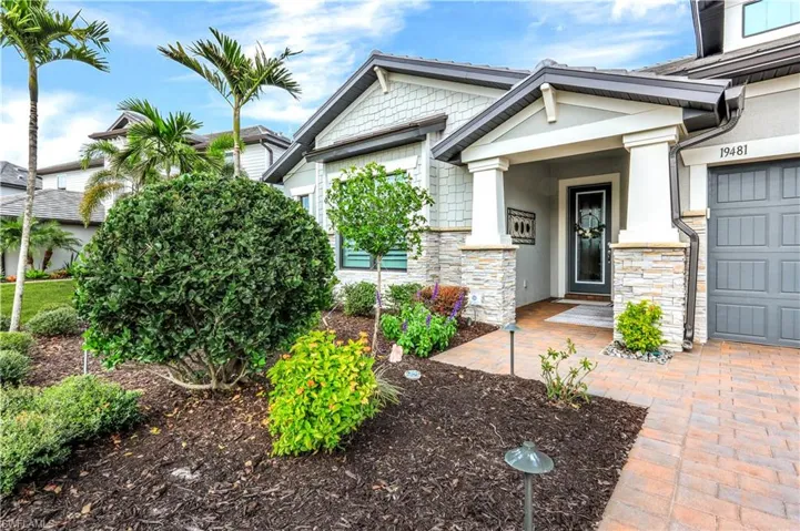 Doorway to property featuring an attached garage, stone siding, and stucco siding