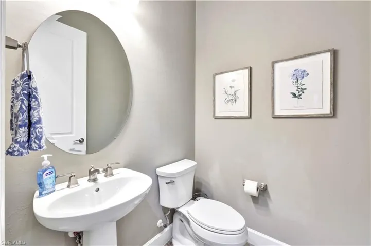 Half bathroom with toilet, baseboards, and a sink