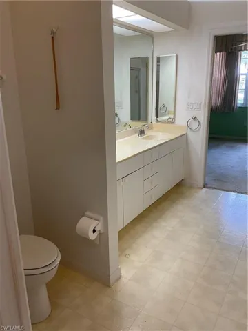 Bathroom with toilet, vanity, and baseboards