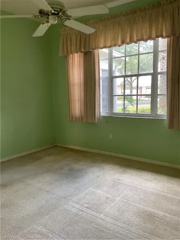 Carpeted spare room featuring baseboards and ceiling fan