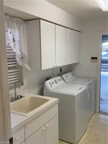 Washroom featuring washing machine and dryer, cabinet space, and a sink