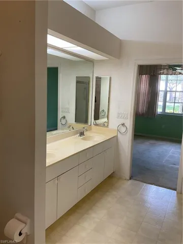 Full bath with double vanity, baseboards, and a sink