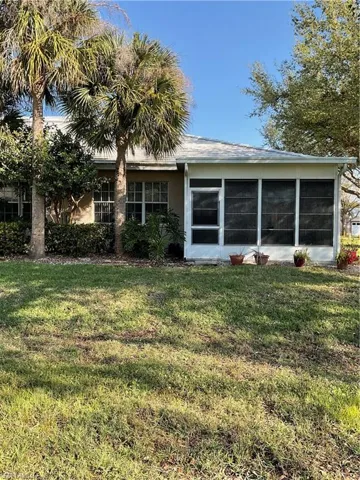 Back of house with a sunroom, a lawn, and stucco siding