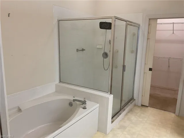 Full bath with a walk in closet, a garden tub, and a stall shower