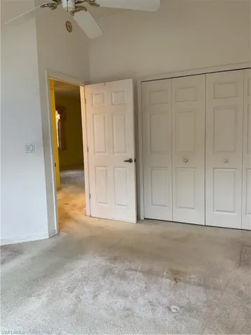 Unfurnished bedroom featuring baseboards, light carpet, and a closet