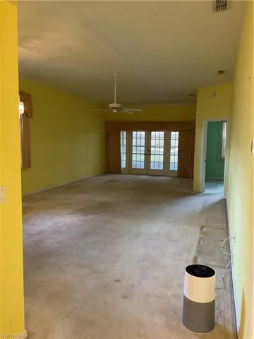 Unfurnished living room with french doors, a ceiling fan, carpet flooring, and baseboards