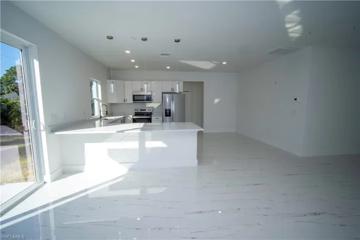 Kitchen featuring appliances with stainless steel finishes, white cabinets, a peninsula, hanging light fixtures, and recessed lighting