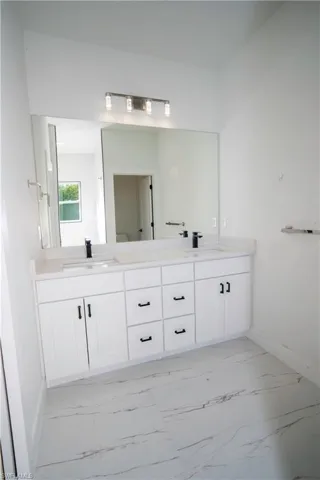 Bathroom featuring double vanity and light marble finish floors