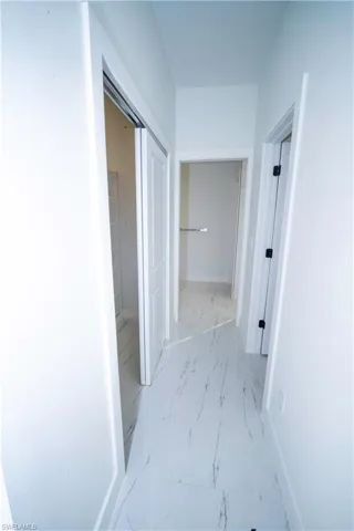 Hallway with baseboards and light marble finish flooring