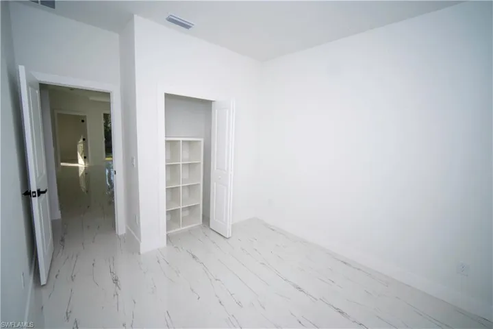 Unfurnished bedroom with baseboards and light marble finish floors