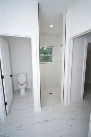 Full bathroom with a marble finish shower, light marble finish flooring, and recessed lighting