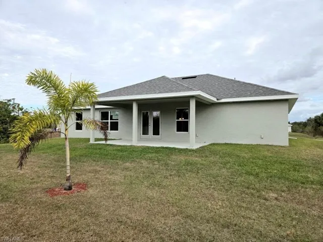 Rear view of property with a patio and a lawn