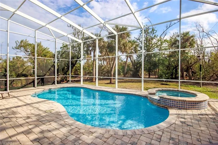 View of swimming pool with glass enclosure, an in ground hot tub, and a patio