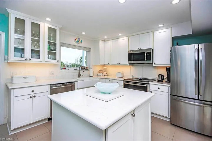 Kitchen with white cabinets, appliances with stainless steel finishes, a center island, and sink