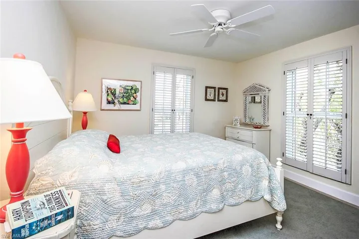 Carpeted bedroom featuring multiple windows and ceiling fan