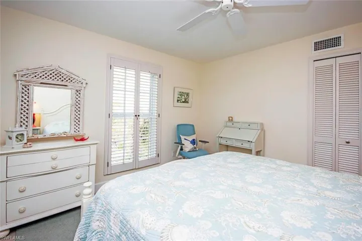 Carpeted bedroom with ceiling fan, multiple windows, and a closet