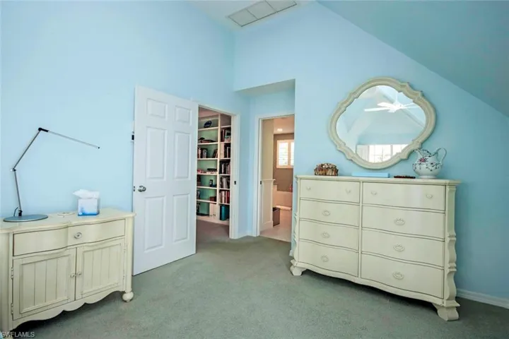 Bedroom with lofted ceiling, light colored carpet, a walk in closet, and a closet