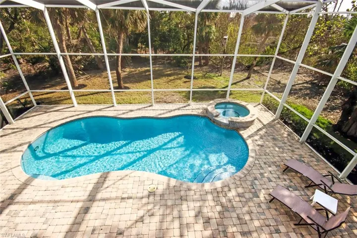 View of swimming pool featuring an in ground hot tub, glass enclosure, and a patio area