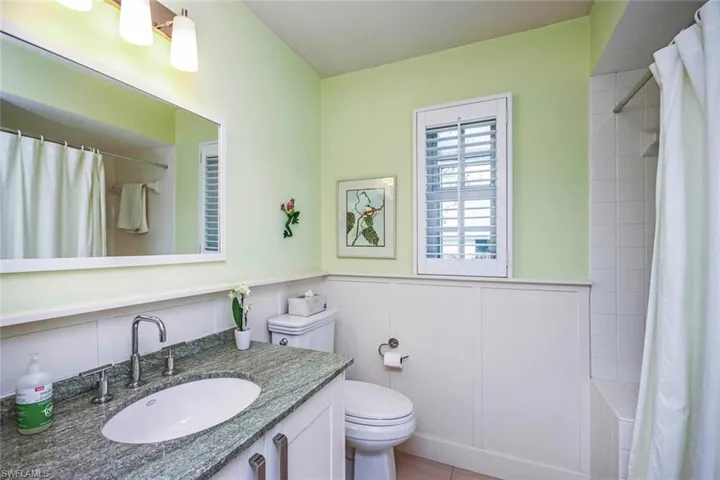 Bathroom featuring tile patterned flooring, a shower with curtain, vanity, and toilet