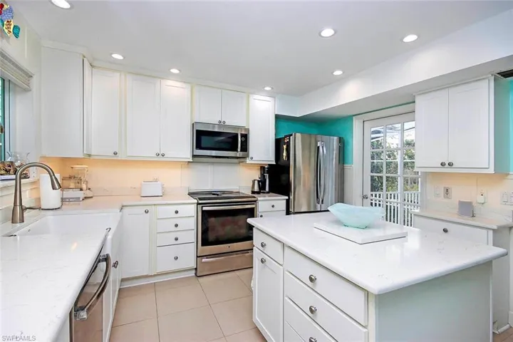 Kitchen with a center island, white cabinetry, sink, and appliances with stainless steel finishes