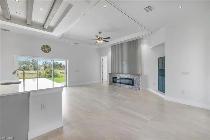 Unfurnished living room featuring a sink, ceiling fan, a tiled fireplace, recessed lighting, and baseboards