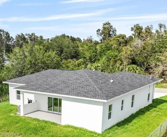 Back of property with roof with shingles, stucco siding, a yard, and a patio area
