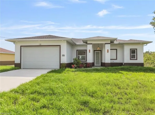 Prairie-style house with driveway, a garage, stucco siding, and a front lawn