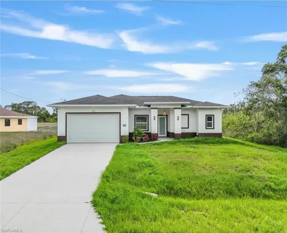 Prairie-style house with an attached garage, concrete driveway, stucco siding, and a front yard
