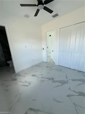 Room featuring marble-look tile flooring, white baseboards, and a black ceiling fan