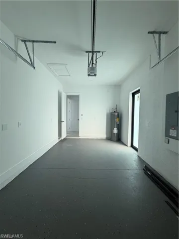 Spacious garage featuring a finished floor coating, automatic garage door opener, interior access door, water heater, and electrical panel