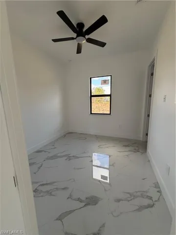 Spacious room featuring white walls, a black ceiling fan with integrated lighting, and a single window with black trim