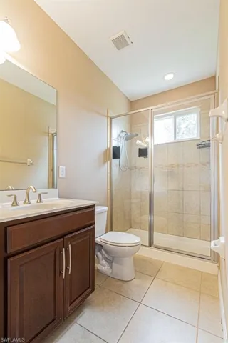 Bathroom with tile patterned floors, a shower with door, vanity, and toilet