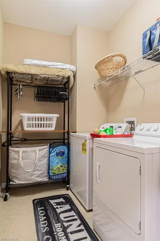 Clothes washing area with washing machine and dryer and light tile patterned floors