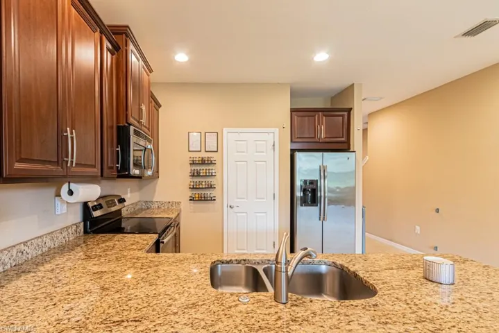 Kitchen featuring light stone countertops, sink, and stainless steel appliances