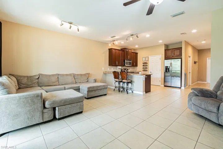 Living room featuring ceiling fan, track lighting, and light tile patterned floors