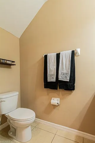 Bathroom with toilet, tile patterned flooring, and lofted ceiling