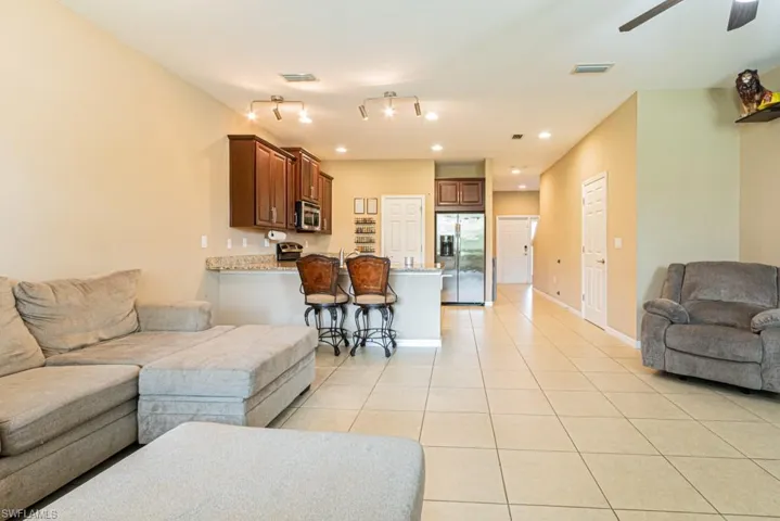 Living room with light tile patterned flooring, track lighting, and ceiling fan