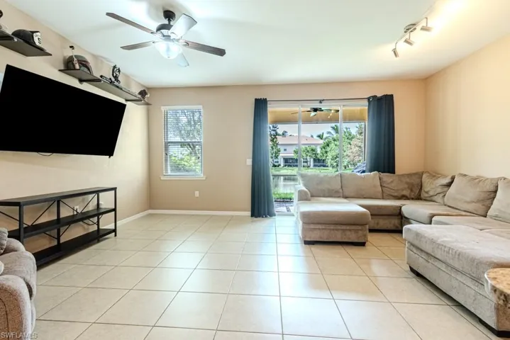 Living room with ceiling fan, rail lighting, and light tile patterned floors
